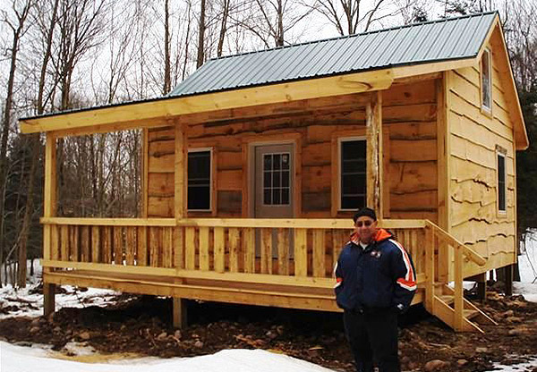 off the grid property for sale new york image of man standing in front of cabin